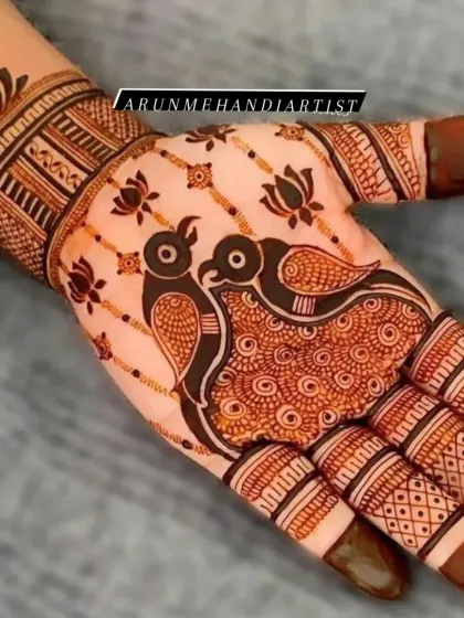 A simple yet striking design featuring two love birds as the centerpiece of the palm. The surrounding lotus motifs and patterned fingers complete this elegant piece of henna art.