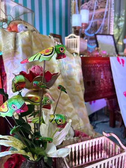 A close-up of charming, brightly painted wooden parrots used as unique decorative accents within a floral arrangement.
