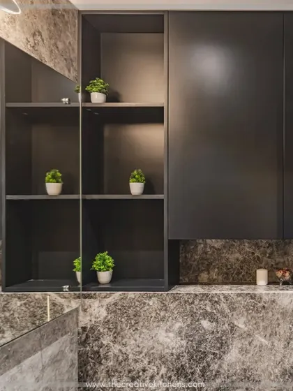 The overhead storage unit combines closed cabinets with open, lit shelving, perfect for displaying decorative items. The large mirror enhances the sense of space and reflects the rich textures of the marble.