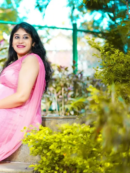 A serene portrait of an expecting mother in a pink dress, taken in a beautiful park setting. Outdoor maternity shoots allow for soft, natural lighting.