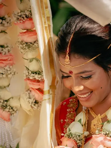 A candid, happy moment from a wedding ceremony. The bride's makeup is subtle and radiant, designed to look beautiful and natural even in bright daylight.