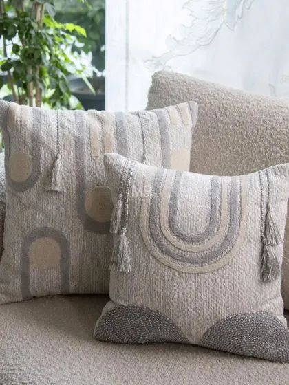 The Contours Cushion Collection adds artisanal character to any sofa. Inspired by the elegance of geometry, these cushions feature modern designs in a soothing palette of grey, white, and beige, with refined details like tafting work and tassels.