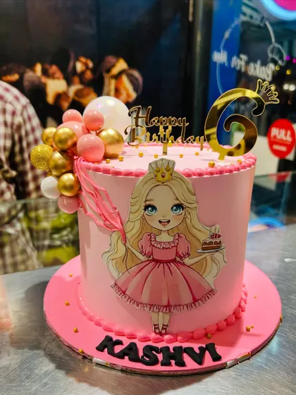 A pretty pink princess cake for Kashvi's 6th birthday. This design features a lovely princess illustration, a gold crown topper, and a cascade of pink and gold decorative balls.