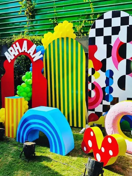 A whimsical photo backdrop with abstract shapes, hot air balloons, and oversized props.