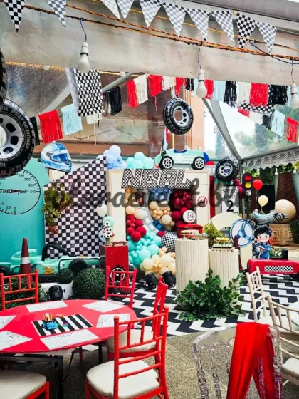 I create a complete race day atmosphere with checkered flag bunting, hanging tires, and themed tables. This overhead view shows how every element works together in a large tented space.