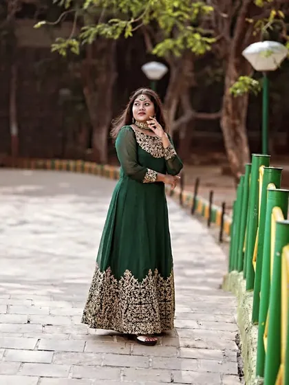 A full-length shot in a park, capturing the elegance of the green Anarkali as the model looks away thoughtfully.