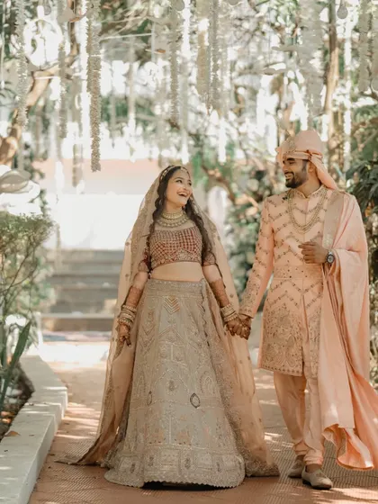 A sweet and romantic portrait of the couple walking hand-in-hand through a garden path. Their smiles and the beautiful setting create a perfect wedding day memory.