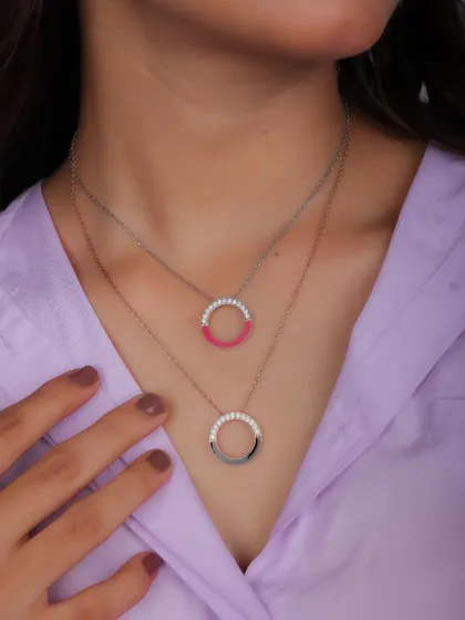 A close-up of a model wearing two layered circular necklaces. This type of shot is effective for showing how to style multiple pieces from a collection.