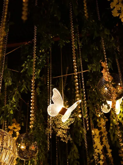 A close-up of the magical sangeet ceiling decor, featuring illuminated butterflies, mini disco balls, and hanging crystal strings.