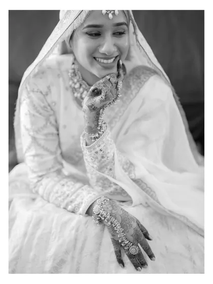 A beautiful black and white portrait of a bride, her joyful smile and intricate henna creating a classic and timeless image.
