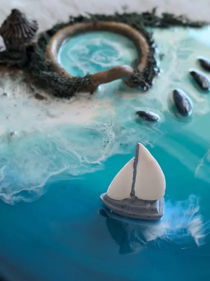 Another angle of the miniature ocean scene, this time focusing on the sailboat gliding across the glossy resin sea.