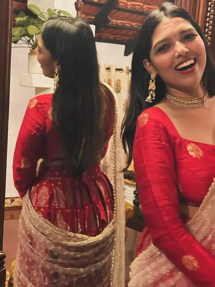 A happy twirl in a custom red lehenga. The reflection shows the beautiful back design of the blouse, a small detail that completes the look.