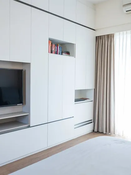 A custom floor-to-ceiling wardrobe in the master bedroom that cleverly incorporates the TV unit and open shelving, maximizing storage while maintaining a clean aesthetic.
