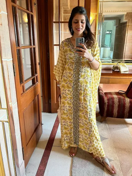 A yellow printed kaftan is the epitome of comfort and style for a festive day at home. The intricate detailing along the neckline adds a touch of elegance to this breezy silhouette.