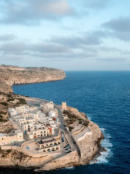 The serene blue waters and historic architecture of a coastal town in Malta. This view captures the unique charm and beauty that makes a destination wedding here so special.