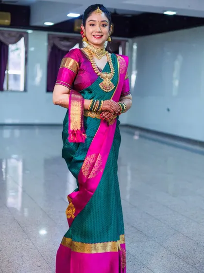 Another beautiful bride in a teal and pink silk saree. The way the pallu is draped over the arm adds a touch of classic elegance to her wedding look.