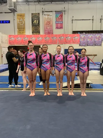 The Xcel team lines up on the floor, ready to represent our gym with pride and skill.