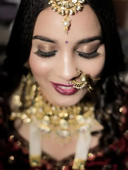A delicate close-up focusing on the bride's stunning eye makeup and jewelry. This shot highlights the artistry of her bridal look, from her long lashes to her shimmering eyeshadow.
