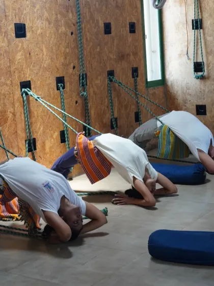 Students using ropes and blankets to practice a supported backbend. Props make challenging poses like this safer and more accessible, allowing for a deeper release in the thoracic spine.