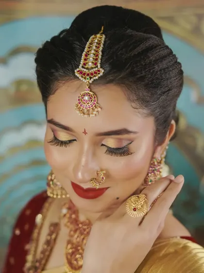 A close-up of a traditional bridal look, focusing on the beautiful harmony between the makeup and jewellery. The golden eyeshadow and classic red lip are signatures of a South Indian bride, designed to make you feel elegant and confident.