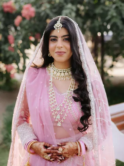 A portrait of modern bridal elegance. The bride's soft makeup, featuring a subtle pink lip and defined eyes, perfectly complements her layered pearl and kundan jewellery.