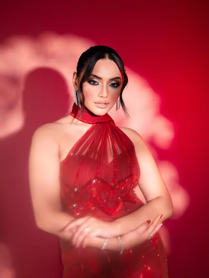 The sheer, embellished fabric of this red gown creates an ethereal yet bold statement. The halter neck design is modern and chic, ideal for a cocktail party.