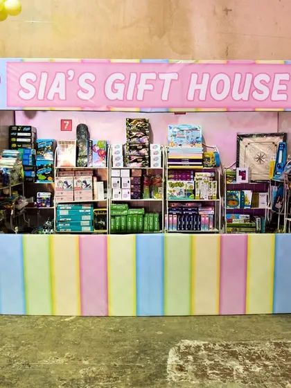 A colorful gift house for a Candyland-themed party, decorated in pastel stripes and rainbow balloons.