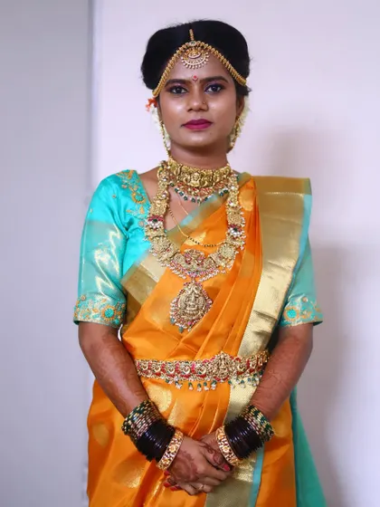This happy client is ready for her wedding ceremony. She is wearing a complete antique gold bridal set, including a matha patti, choker, haram, and Vaddanam.