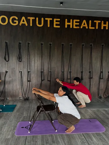 Malasana (Garland Pose) with chair support. This helps students who have tight hips or ankles to access the benefits of the squat, such as improved digestion and pelvic floor health.
