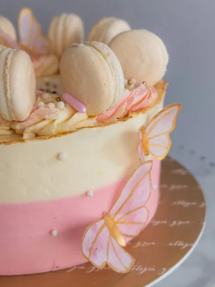 A detailed shot of the butterfly celebration cake, showing the texture of the buttercream and the handcrafted wafer paper butterflies with gold accents.
