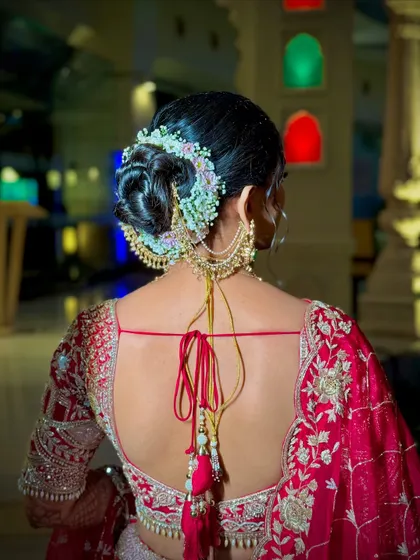 A detailed shot of a beautiful bridal bun, adorned with pastel-colored flowers and a traditional hair accessory.