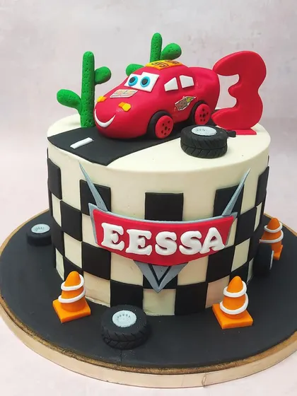 This McQueen Car Cake puts the star racer front and center on a road, complete with desert cacti, tires, and traffic cones for a full racing scene.