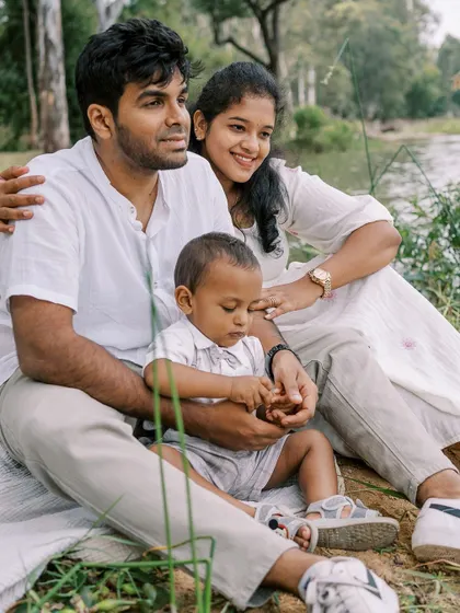 A family sitting by a lake. The peaceful scenery provides a stunning backdrop for this serene family portrait.