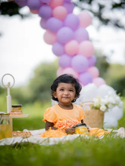 A happy smile during an outdoor picnic session. The colorful balloon arch adds a celebratory touch to this beautiful natural setting.