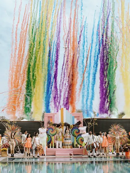 A spectacular moment from a poolside Haldi, where a rainbow of color smokes erupts behind the couple and their entourage, creating a breathtaking photo opportunity.