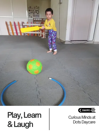 A child practices his batting skills in our play area. Gross motor activities like this are essential for physical development, helping children build strength, balance, and coordination.