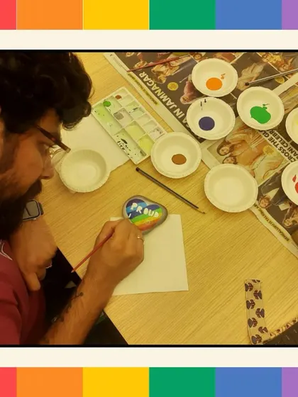A participant carefully paints a rainbow heart on a pebble, a personal expression of support and pride.