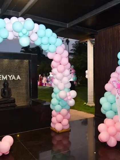 This butterfly-themed entrance features a pink and mint balloon arch and a matching welcome sign. The setup creates a cohesive and beautiful welcome area for an outdoor event.