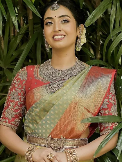 This client looks like a dream in her green and red saree. The custom-designed red blouse with intricate floral embroidery adds a vibrant touch to her look for the wedding festivities.