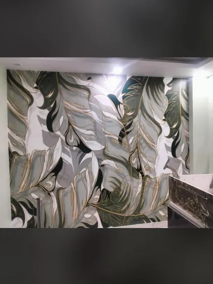 A close-up of a custom wallpaper with a large, abstract feather or leaf pattern. The mix of green, grey, and gold gives it a modern and sophisticated look.