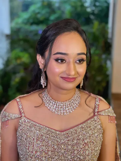 A beautiful soft glam look for Sneha's reception. The makeup features a subtle smokey eye and a glossy pink lip, paired with a modern half-up hairstyle.