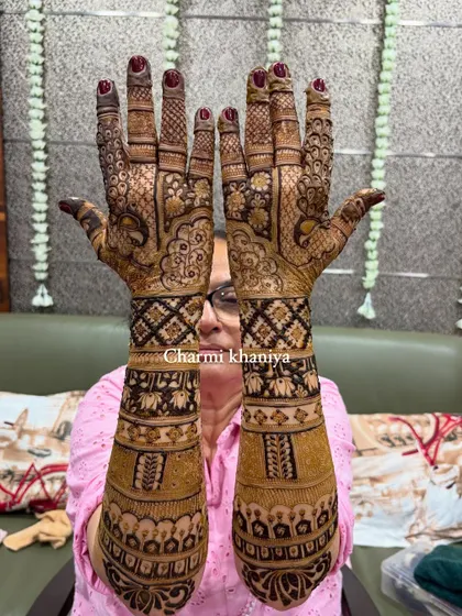 A full view of the groom's mom's heavy traditional back of hand mehendi. She looks so happy!