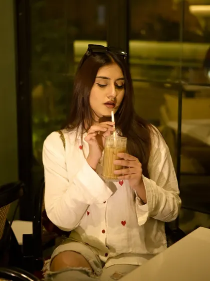A solo coffee date look. A casual white shirt with red hearts, paired with ripped jeans.