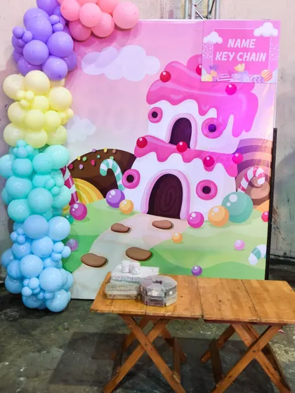 A 'Name Keychain' making station set against a colorful Candyland backdrop, another great personalized party favor activity.