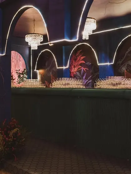The sangeet bar features elegant arches, chandeliers, and neon light strips, creating a glamorous and inviting space for guests to grab a drink.