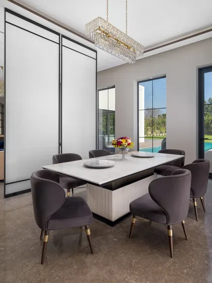 Another view of the dining room, showing its connection to the outdoors with large windows looking out onto the pool and garden. The plush velvet chairs invite long, comfortable meals with family and friends.