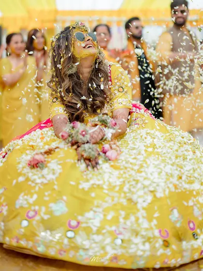 A beautiful portrait of the bride, looking up with a joyful expression as she is covered in a sea of white and yellow flowers.
