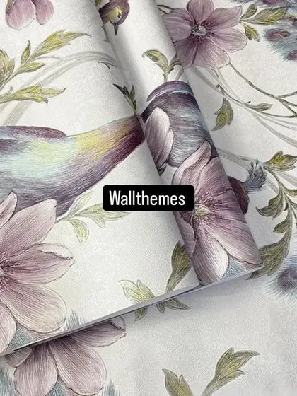 A close-up of a white wallpaper roll with a delicate, painterly design of birds and purple flowers.