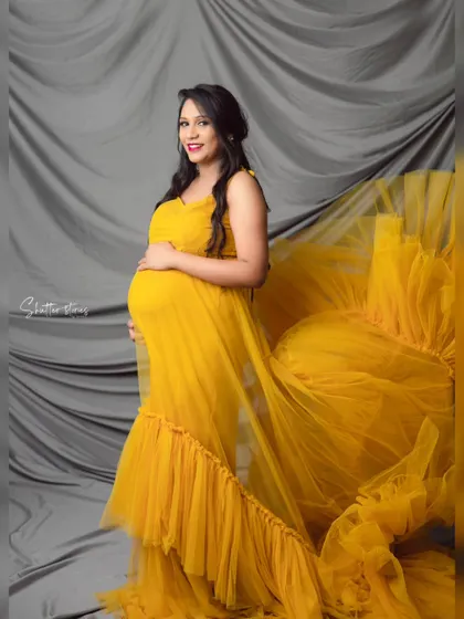 The dramatic flair of the yellow tulle gown is captured perfectly as it flows behind the mom-to-be in this dynamic studio shot.