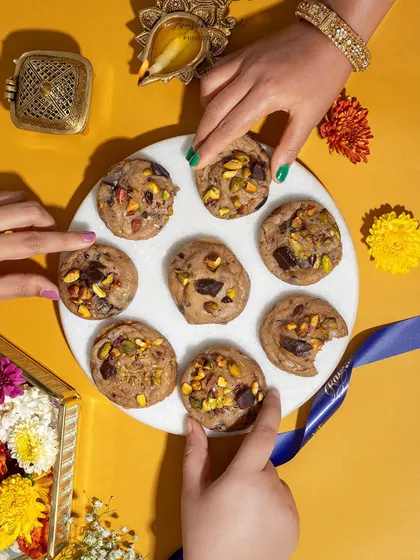 A fun, interactive flat lay with multiple hands reaching for festive cookies on a marble platter.